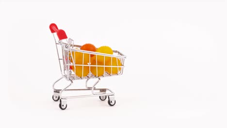 el carrito del supermercado se mueve lleno de tomates de cereza amarillos amontonados con gotas de agua. aislados en el fondo blanco. primer plano. macro.