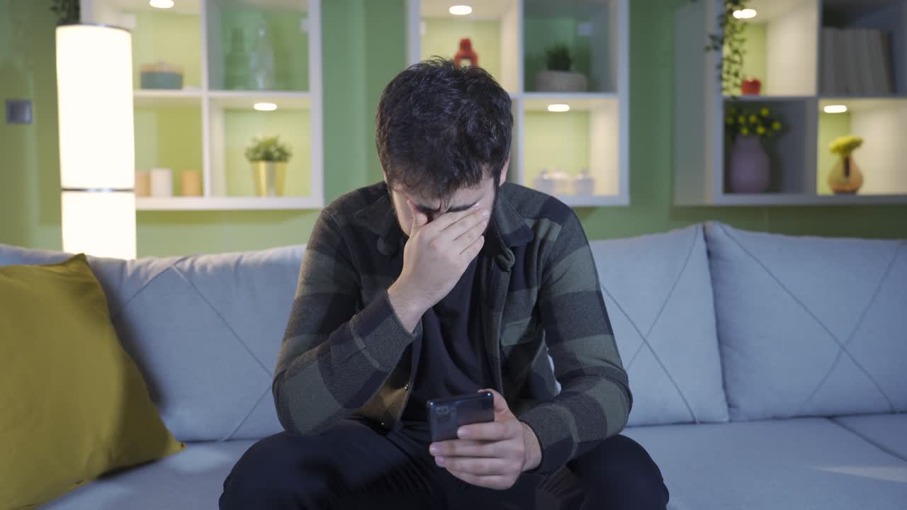 전화로 실망스러운 소식을 받은 젊은 남자는 화가 나서 울고 있습니다.