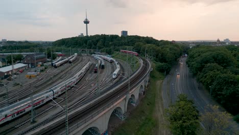 Train-depot-and-railway-yard-aerial-view-of-Cologne-in-Germany-on-a-sunny-evening-with-the-tv-tower-in-the-background-and-a-lot-of-trains-in-the-yard-sidings