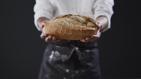 video de un cocinero sosteniendo un pan sobre un fondo negro