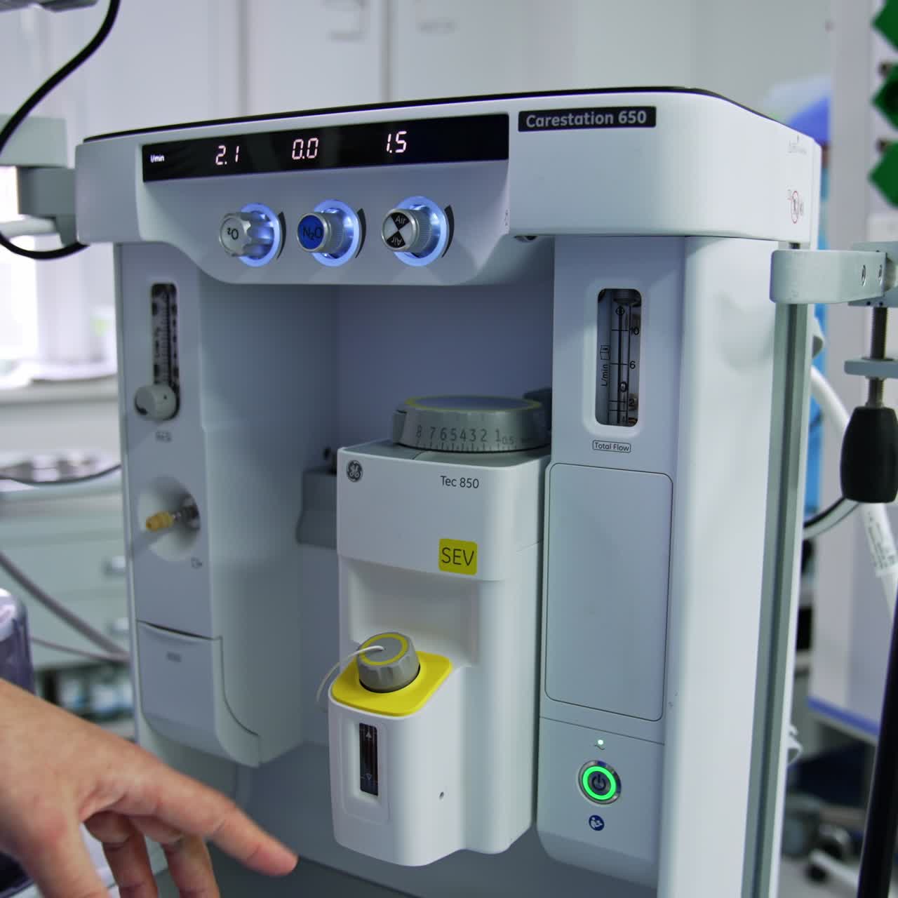Male hand turns the big handle on the medical apparatus. Doctor is setting parameters on the equipment in modern surgery room