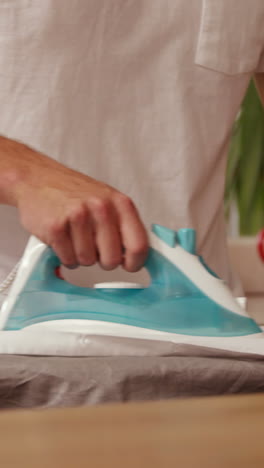 midsection of a man ironing a shirt