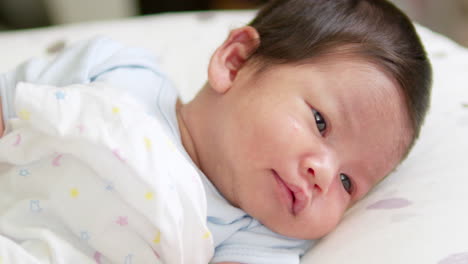 a small newborn baby is cooing and stretching as it looks at things and people that are around in the room