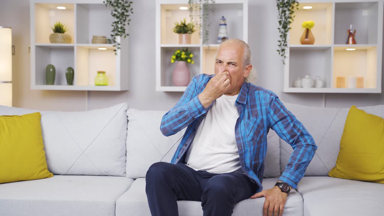 el anciano, que huele el mal olor en la casa, está perturbado por el mal olor.