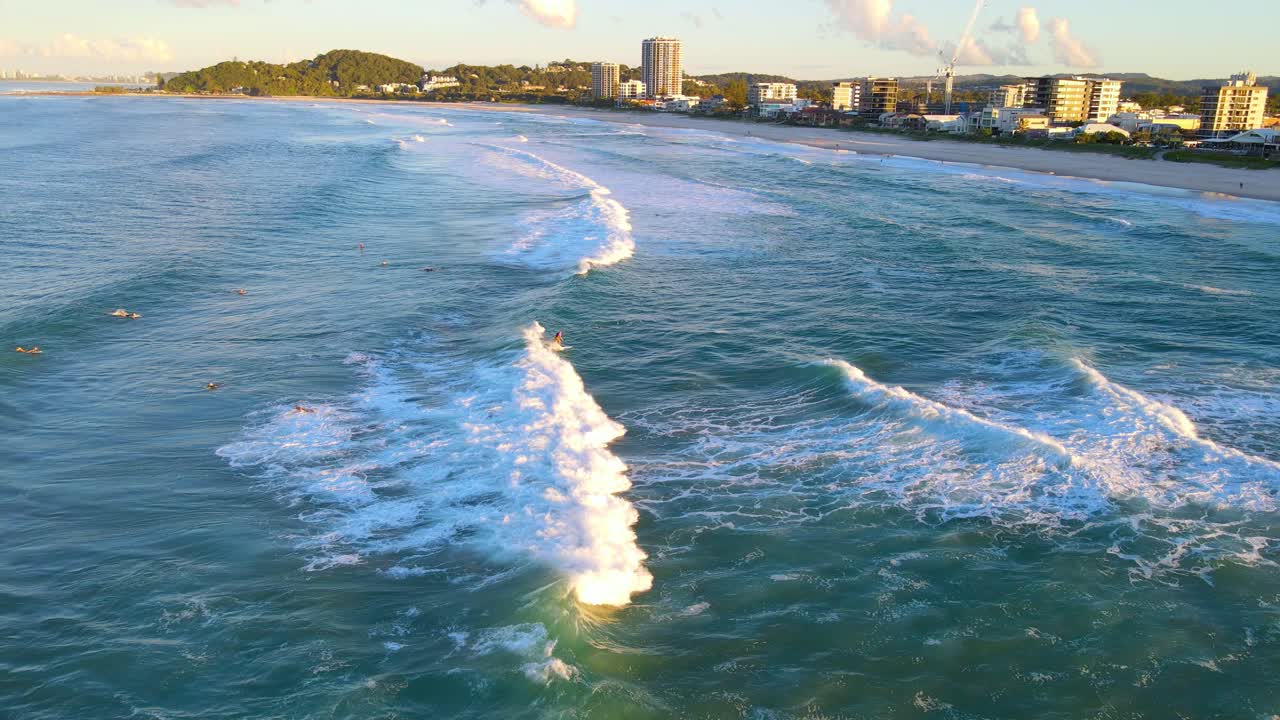 일출 동안 서핑하는 서퍼들이 즐기는 돌진하는 파도 - 호주 qld의 팜 비치에서 서핑 장소