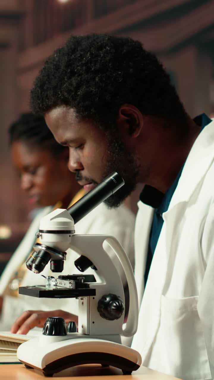 Scienziato afroamericano che lavora con un microscopio e sorride