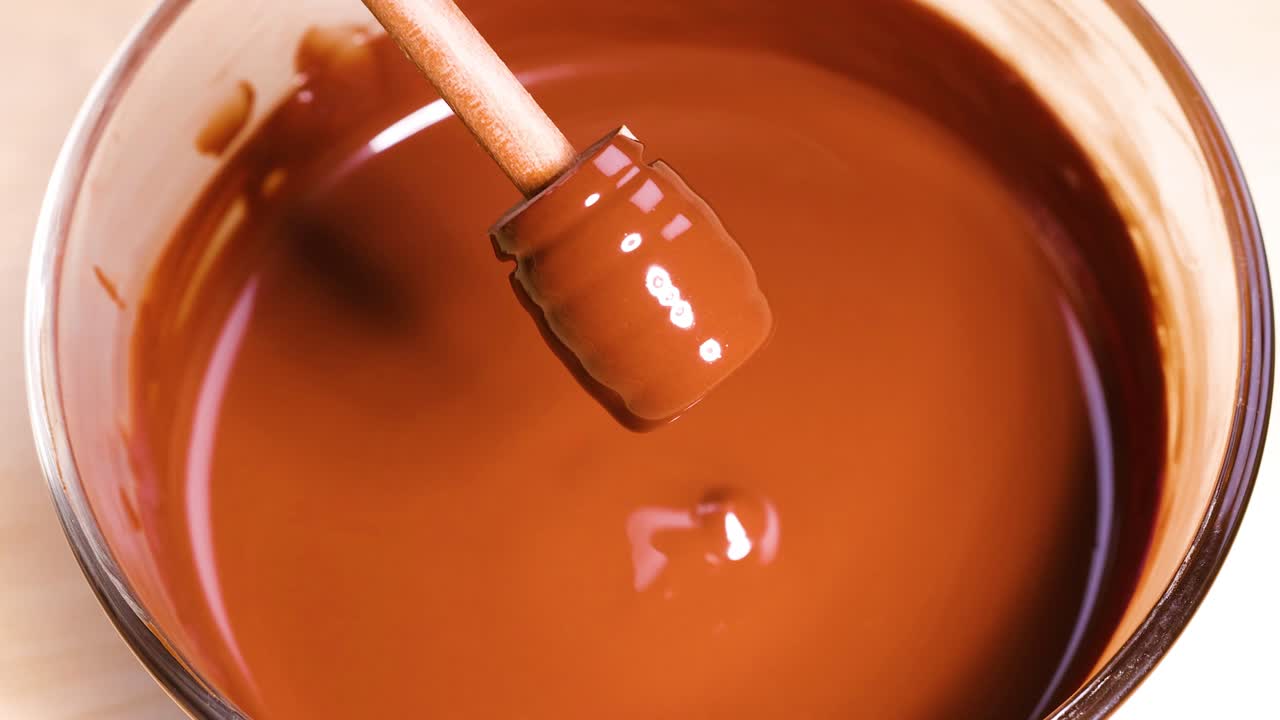 Wooden stick stirring smooth melted chocolate