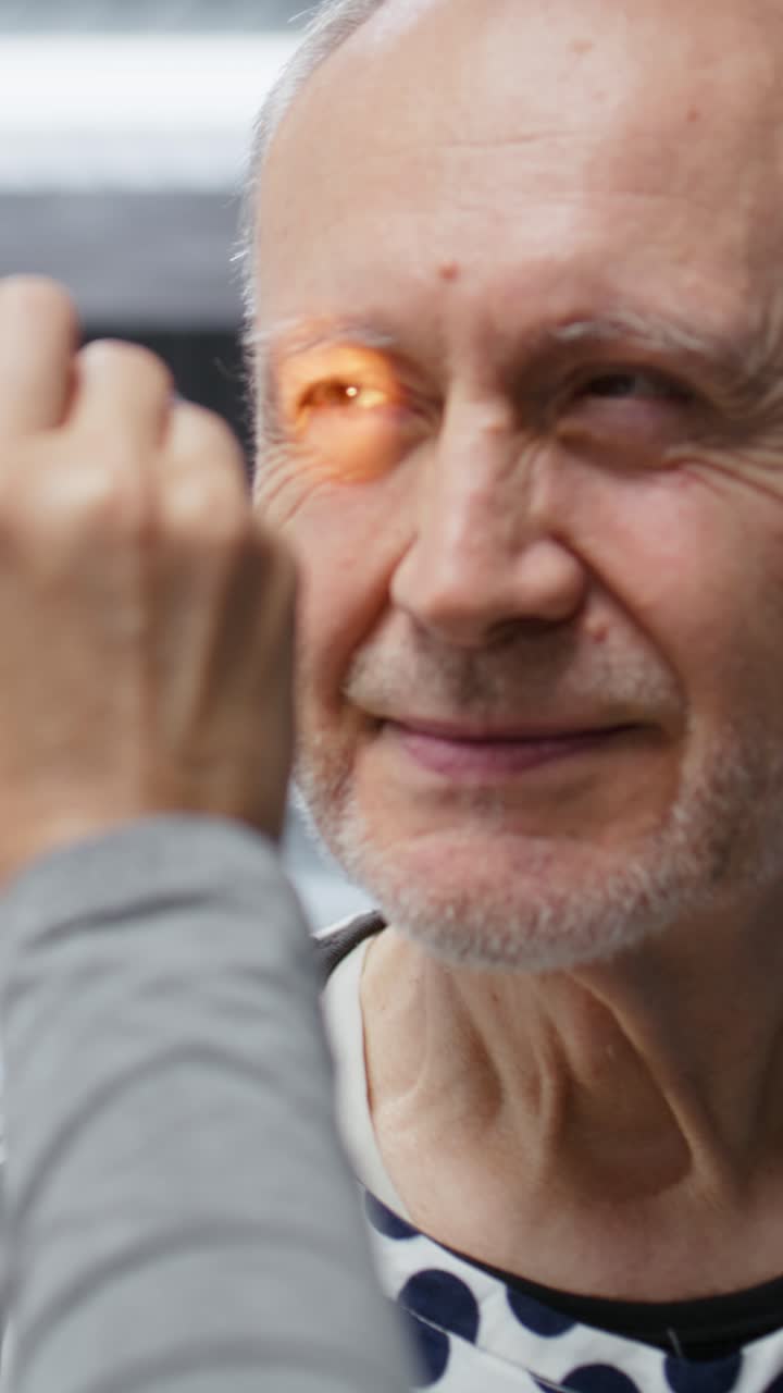 Vertical Video Woman medic using light pen to examine senior patient for clinical trial