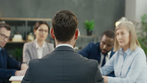 Rear-View-Of-Businessman-Sitting-At-Table-With-Business-Colleagues-Discussin-About-Work-In-The-Office