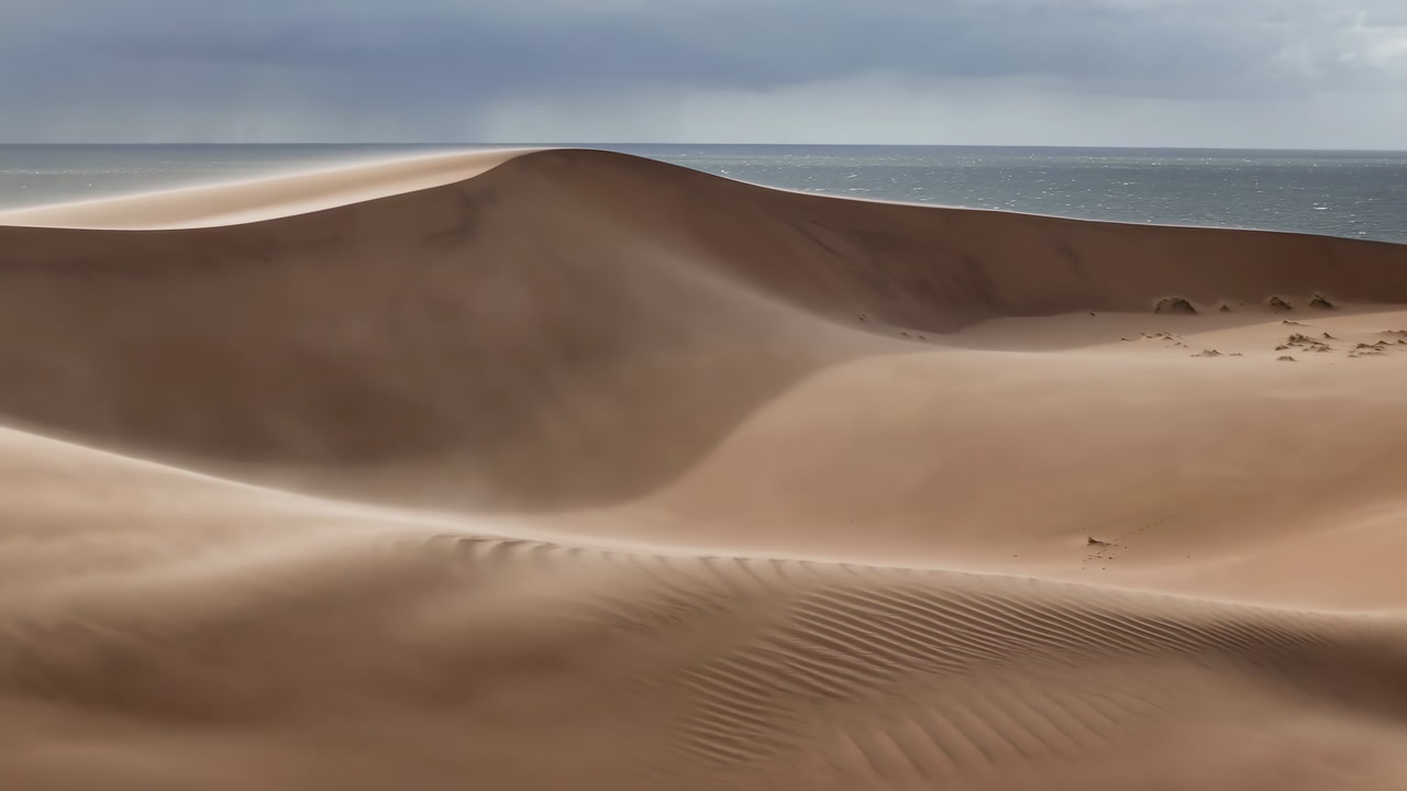 Vast Sand Dune Landscape With Sea Under Moody Sky, Windswept Ripples Sculpted By Wind, Soft Golden Light