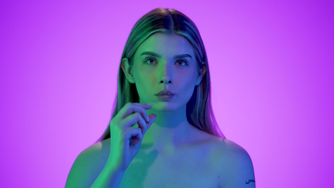 mediano primer plano de una mujer bastante atractiva sosteniendo un chip de patata estriado en la cámara y luego comiéndolo con deleite frente a un fondo púrpura con contrastes azules en su cara en cámara lenta