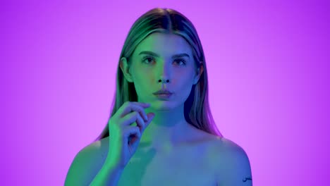 Medium-close-up-of-a-pretty-attractive-woman-holding-a-fluted-potato-chip-into-the-camera-and-then-eating-it-with-relish-in-front-of-a-purple-background-with-blue-contrasts-in-her-face-in-slow-motion