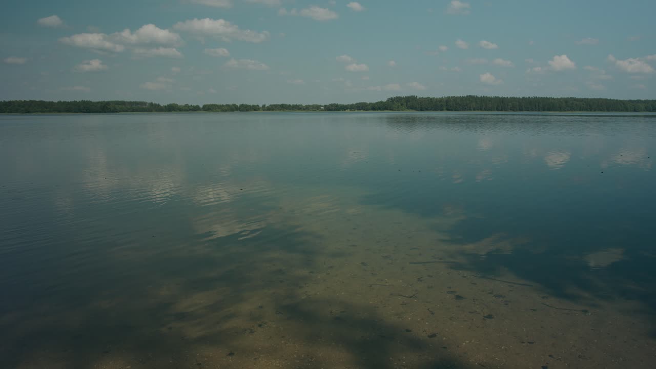 Ondas en aguas poco profundas de un lago lituano con el reflejo del cielo azul