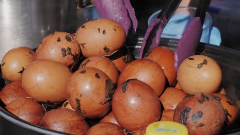 chinese century eggs or tea egg in boiling water close-up. chinese egg-based culinary dish made by preserving duck, chicken, or quail eggs in a mixture of clay, ash, salt, quicklime, and rice hulls for several weeks to several months.korean mayak eggs or mayak gyeran are boiled eggs marinated in a f