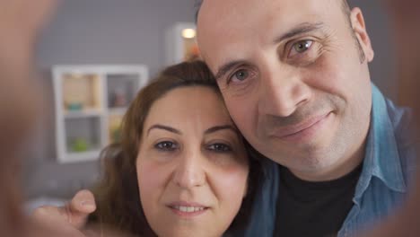 couple looking at camera making heart sign and smiling.