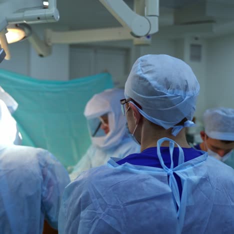 teamwork of doctors in the operating room. group of medical workers in blue uniform perform a surgery in hospital. the end of pandemic.