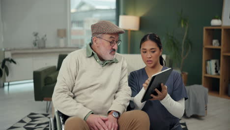 elderly man in wheelchair with caretaker discussing medical information on a tablet
