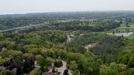 Drohne-Fliegt-über-Die-Grünfläche-Von-Toronto-Mit-Einer-Autobahn-Und-Einem-Golfplatz-Im-Hintergrund