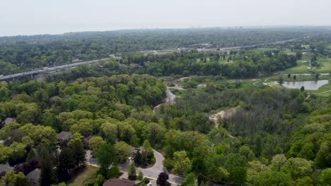 drone volando sobre el espacio verde de toronto con una carretera y un campo de golf en el fondo