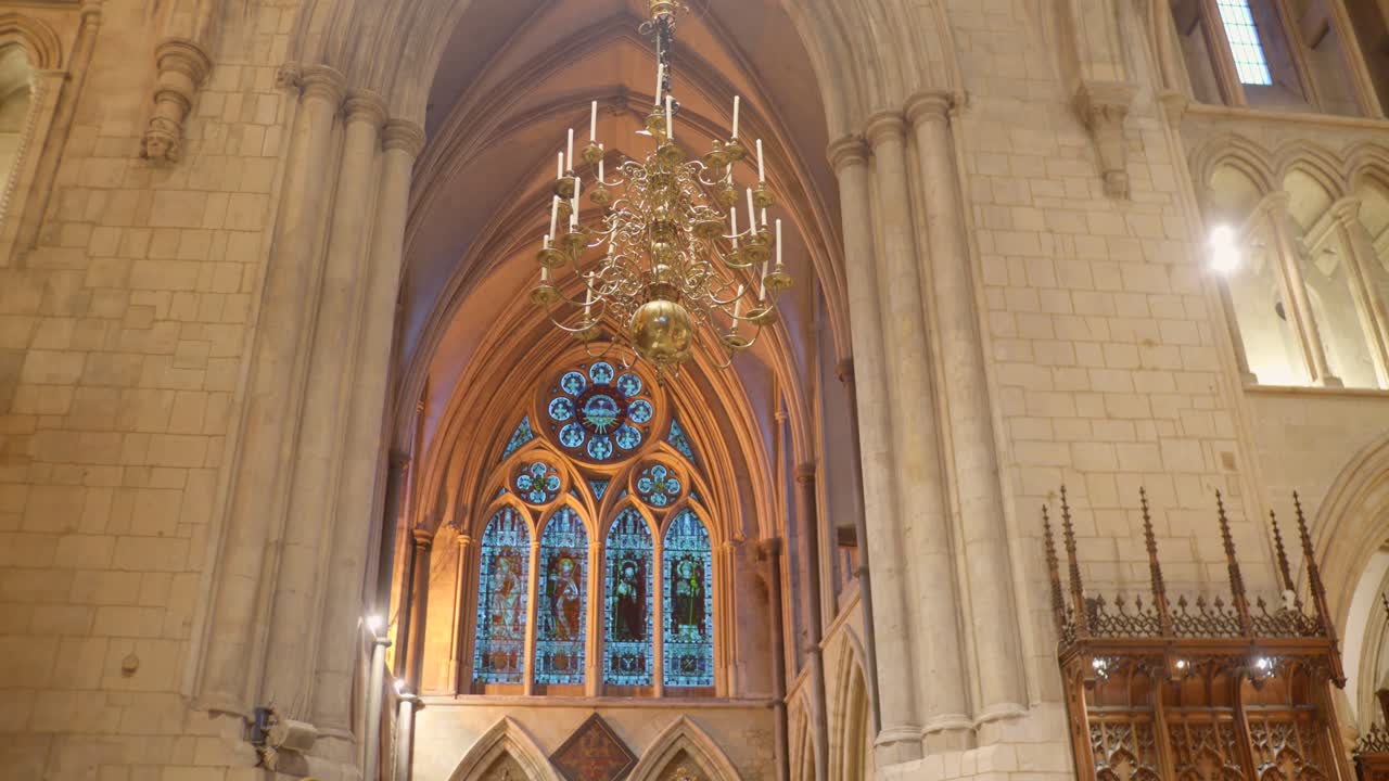 Interior view of Southwark Cathedral showing stained glass window, chandelier and gothic arches
