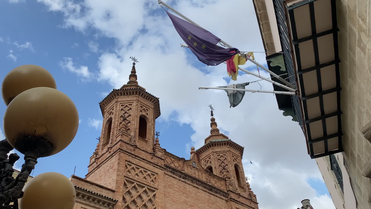 Jerez de la Frontera cathedral rising above a line of green trees under a bright sky filled with scattered white clouds on a warm afternoon