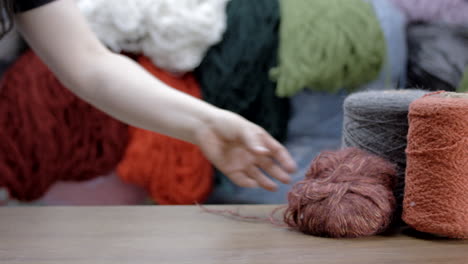 Hand-leaves-a-ball-of-wool-thread-on-the-table