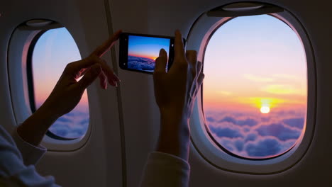woman taking a photo of the sunset from an airplane window