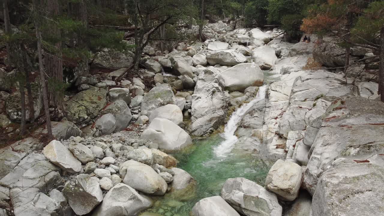 Static high angle shot of peaceful small waterfall in stream river in Restonica, Corsica