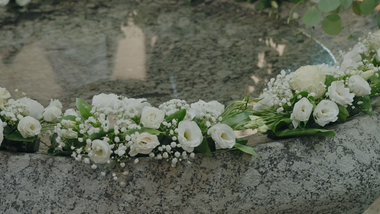 stone baptismal font decorated with white floral arrangement for ceremony