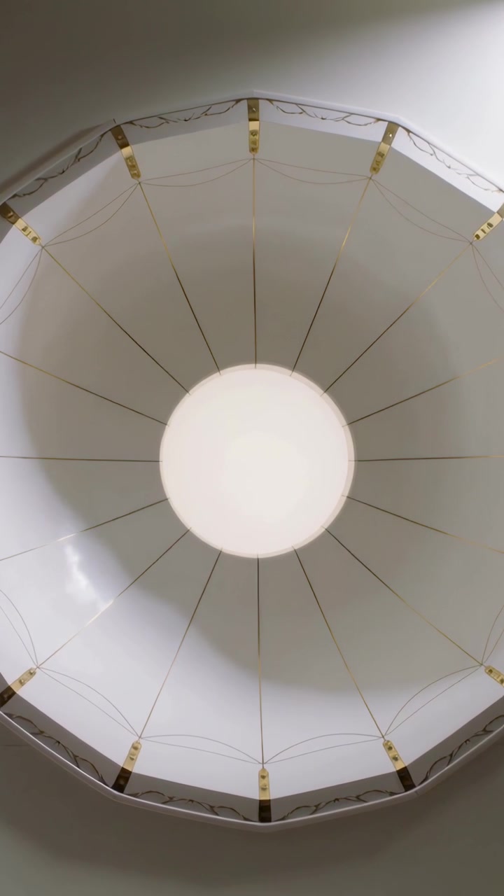 Video verticale: Telecamera inclinata che mostra un diffusore rotondo che cambia angolazione sul soffitto, con clip dorate.