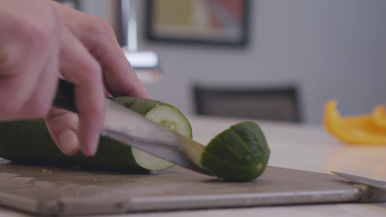 A slow motion shot of a cucumber being cut into thin slices