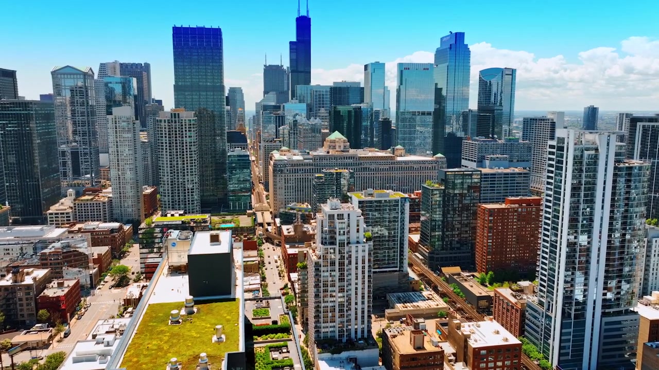 Vista do centro ensolarado de Chicago, Illinois, EUA. Arquitetura de baixa altura ao fundo de edifícios altos com janelas espelhadas. Voo sobre a casa com grama verde no telhado.