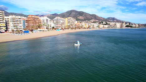 aerial dolly across fuengirola hills beach with small tug boat