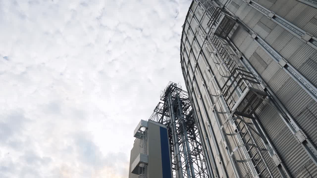 Modern agricultural complex outdoors. Exterior of high metal building of a factory. Aluminum construction for drying and processing crop. Grain elevator