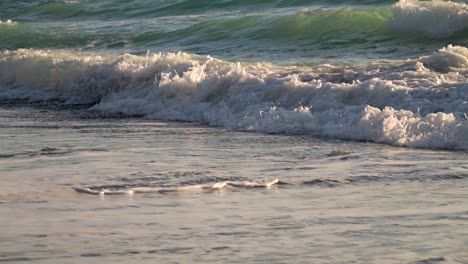 Beautiful close up cinematic slow motion shot of waves rolling in on beach