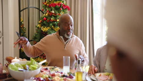 Feliz-Y-Diversa-Pareja-De-Ancianos-Abrazándose-En-La-Mesa-De-La-Cena-De-Navidad-Con-Amigos,-Cámara-Lenta