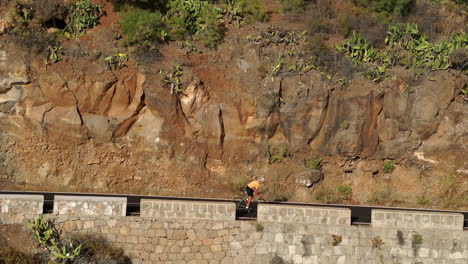 un hombre con una camiseta amarilla en una bicicleta de carretera deportiva viaja por la carretera ubicada en lo alto de las montañas