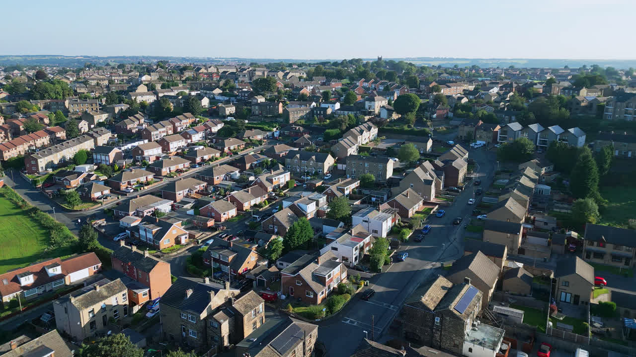 Drone-captured aerial footage reveals Dewsbury Moore Council estate, UK, with red-brick housing and Yorkshire's industrial landscape on a sunny summer morning