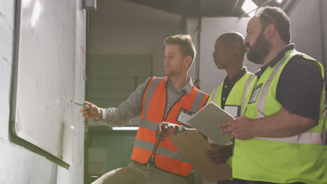 two caucasian and an african american male factory worker at a factory in discussion