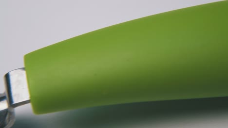 Gemüseschäler-Mit-Grünem-Griff-Liegt-Auf-Weißer-Oberfläche