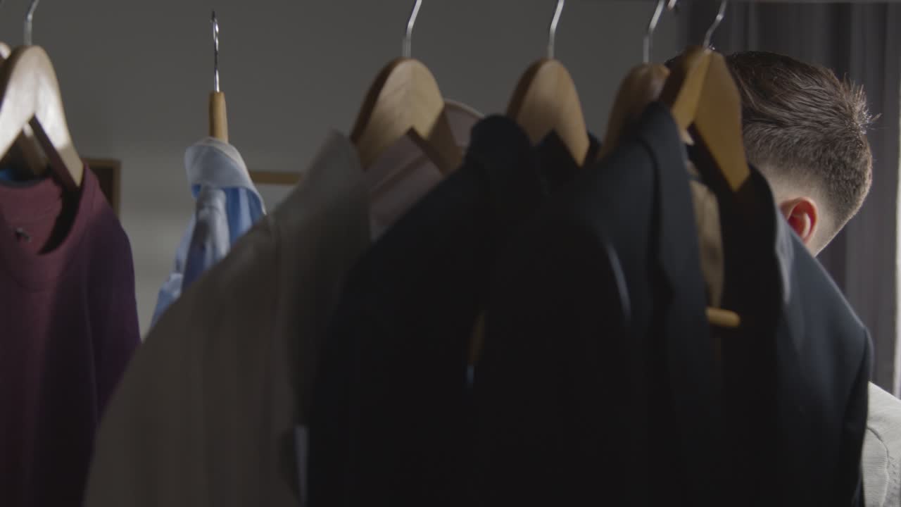 취업 면접을 위해 옷장에서 비즈니스 정장을 선택하는 집에 있는 청년 1