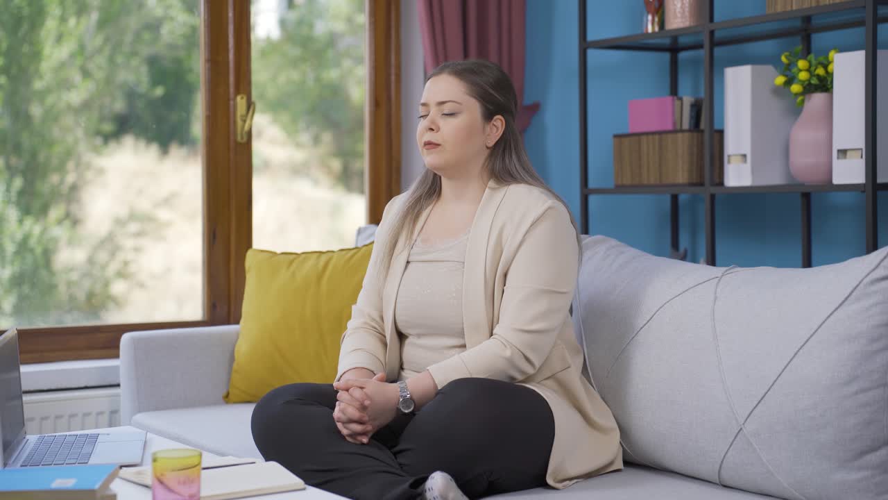 창문 앞의 젊은 여성은 깊은 숨을 쉬고 눈을 감습니다.