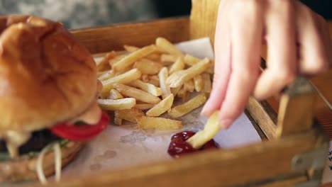 camera moves from female hands taking french fries and showing her smiling face while taking. slow motion shot