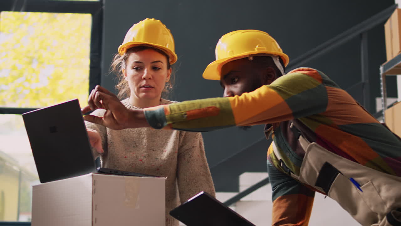 Warehouse workers discussing shipment details on a laptop