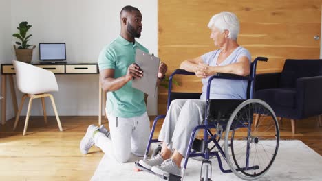 video of happy african american male physiotherapist examining caucasian senior woman on wheelchair