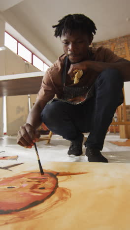 fotografía vertical de un artista afroamericano que pinta un retrato en un estudio