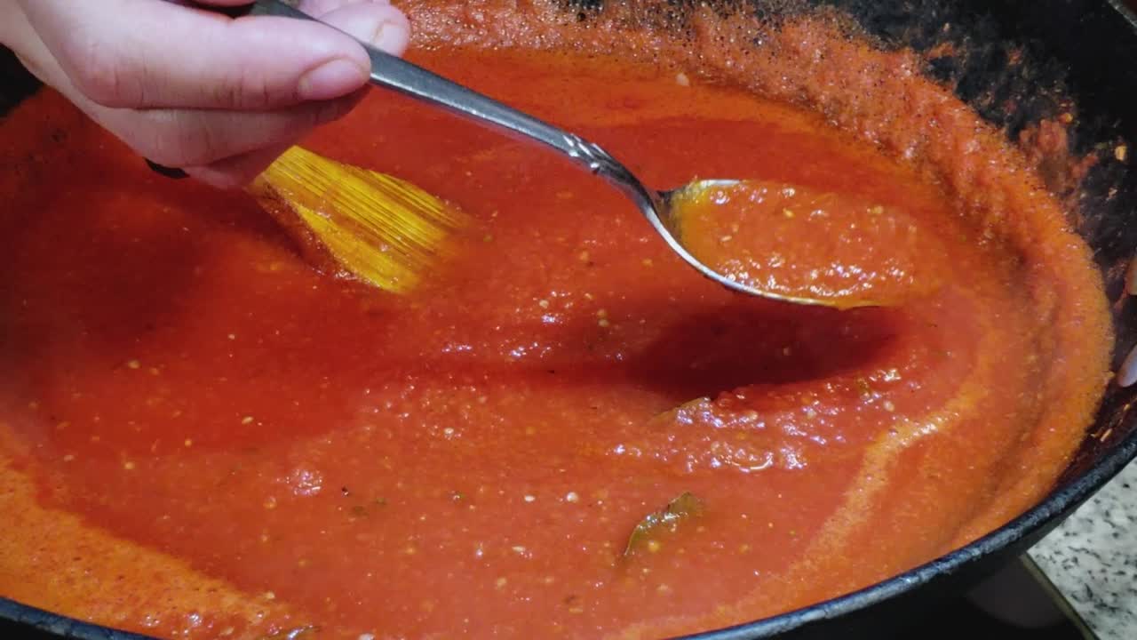 chef usando una cuchara para mezclar y probar la consistencia de la salchicha napoli