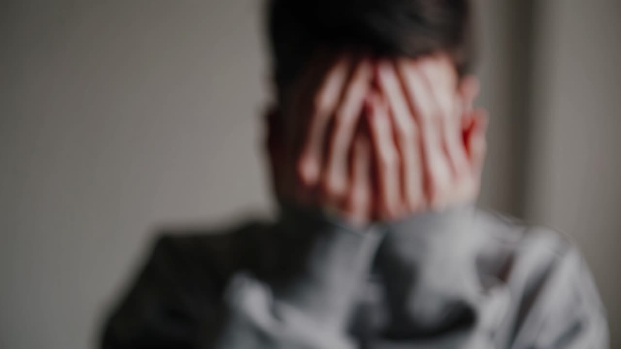 Un primer plano de un fotograma de vídeo captura a una persona cubriéndose la cara con las manos, transmitiendo emoción.