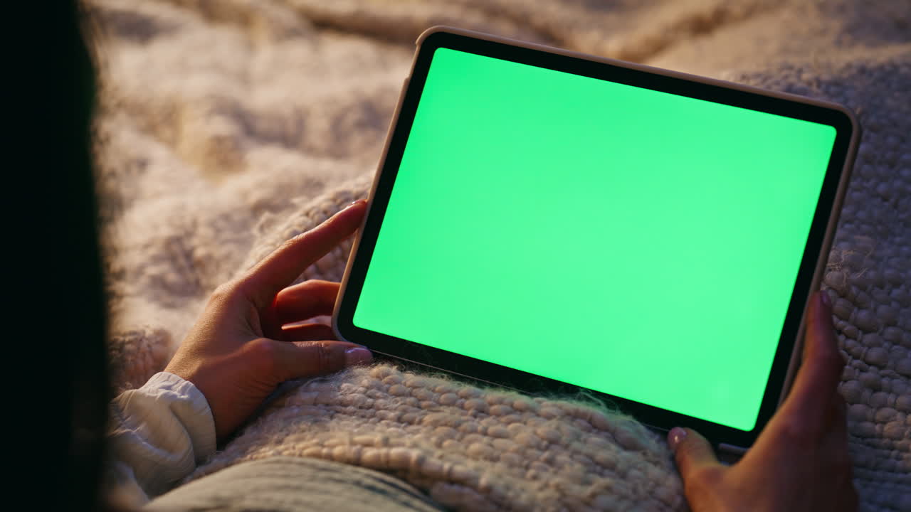 Woman hand holding mockup tablet lying bed closeup. Lady watching online video
