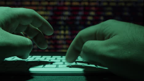 close-up of hands typing on a keyboard at night